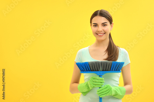Female cleaner on yellow ba...
