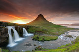 Amazing sunset the top of Kirkjufellsfoss waterfall with Kirkjufell mountain in the background on the north coast of Iceland's Snaefellsnes peninsula taken white a long shutter speed.