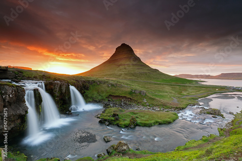 Amazing sunset the top of Kirkjufellsfoss waterfall with Kirkjufell mountain in the background on the north coast of Iceland s Snaefellsnes peninsula taken white a long shutter speed.