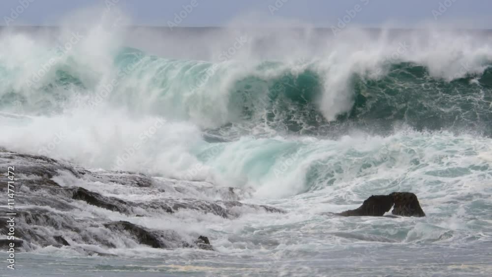 A series of foaming waves crashing against a rocky ledge A series of foaming waves crashing against a rocky ledge
