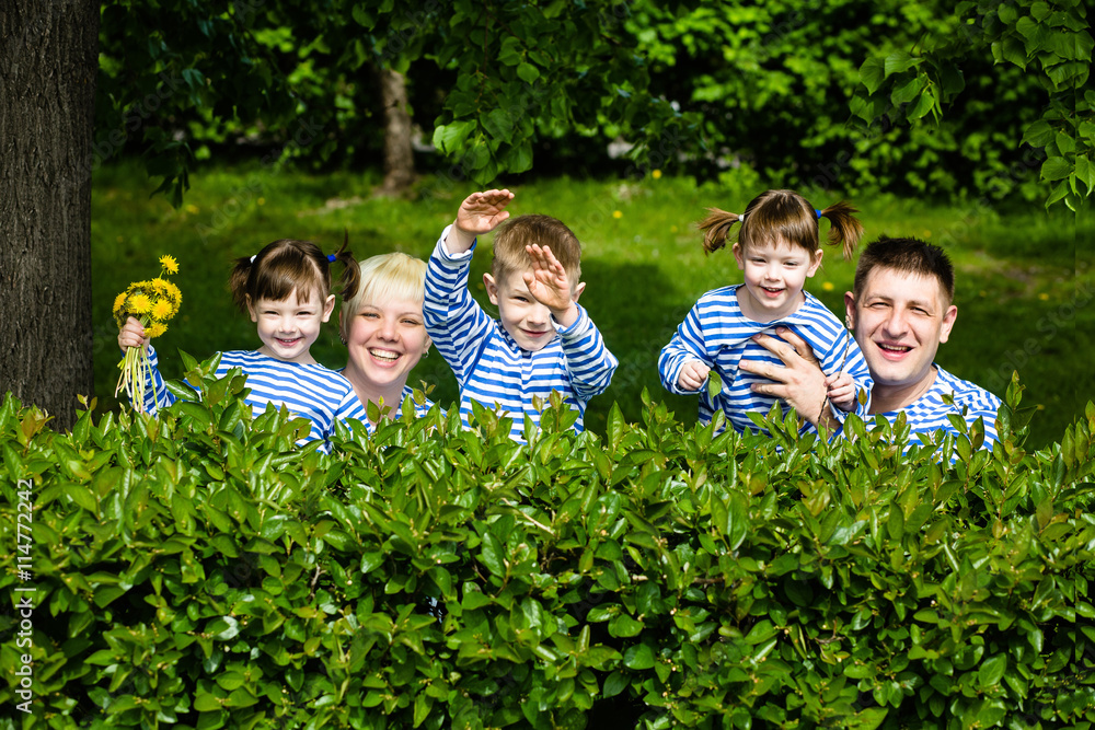 Fototapeta premium Happy family: mother, father, son and daughters-twins having fun in the park on a sunny summer day