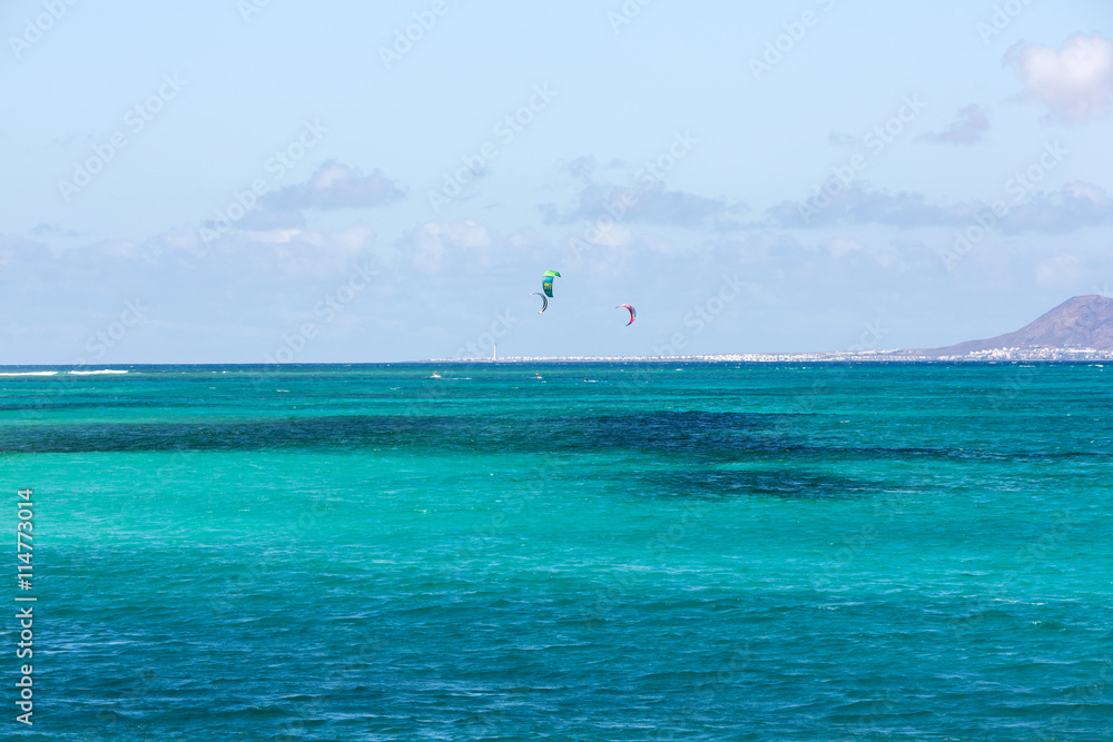  kitesurfers surfing on a flat azure water of Atlantic ocean in Corralejo. Fuertevetnura, Spain