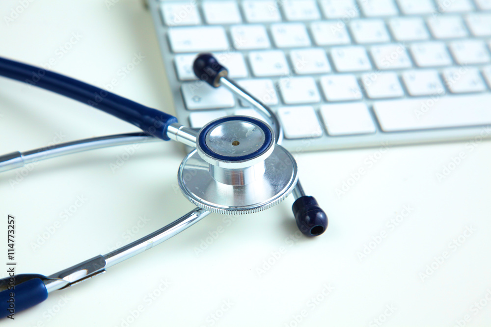 A medical stethoscope near a laptop on a wooden table, on white A medical stethoscope near a laptop on a wooden table, on white