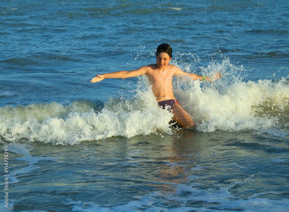 young boy plays by jumping the waves