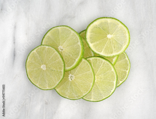 Lime slices on a marble cutting board top view.