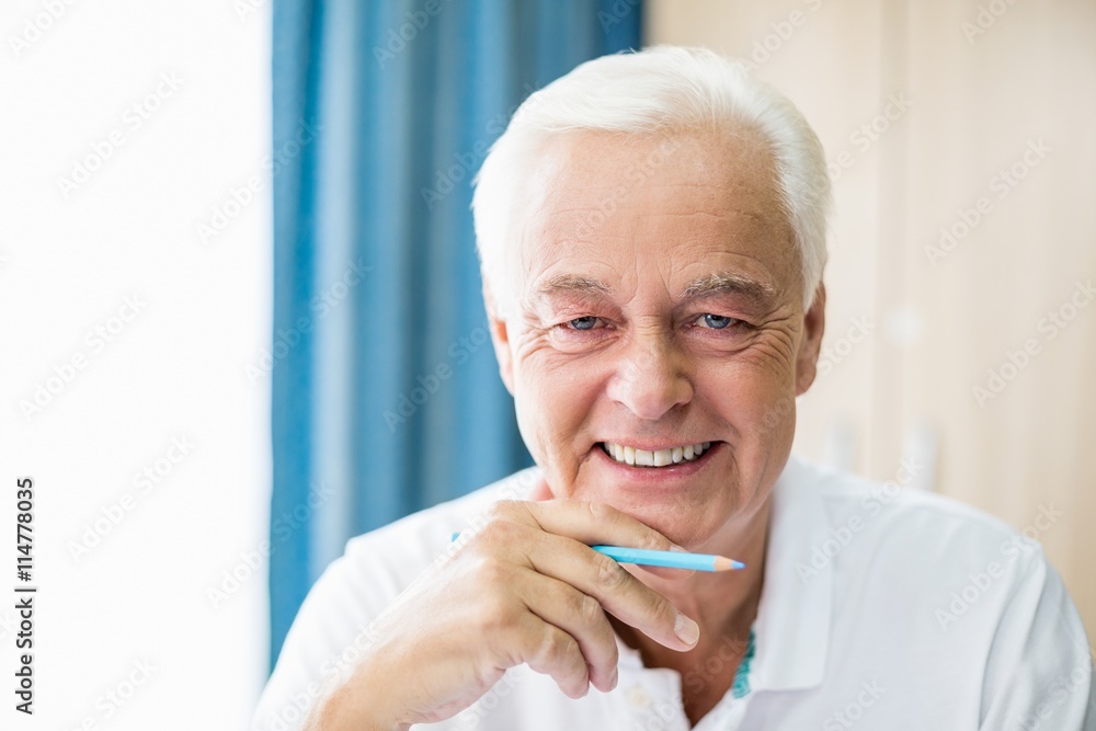 Smiling senior holding coloured pencil Smiling senior holding coloured pencil