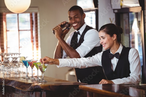 Female bartender garnishing cocktail with olive photo