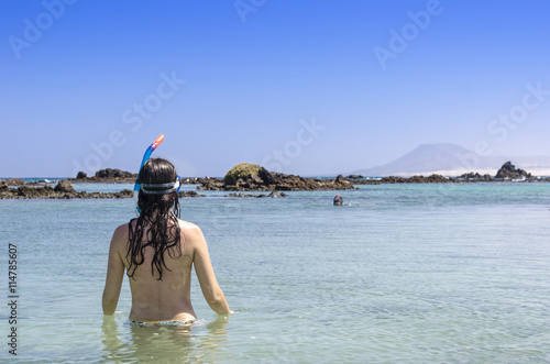 Rear View of brunette woman wearing snorkel and mask looking to