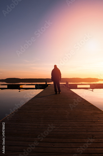 A man goes on the wooden pier in the sunset