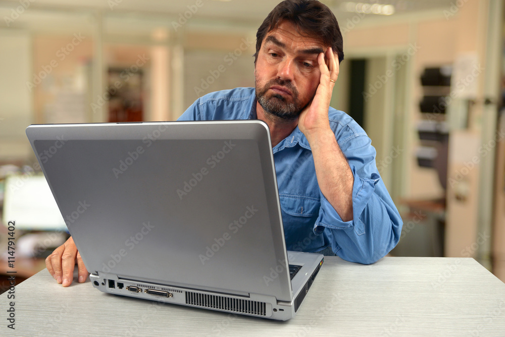 Homme peu motivé devant son ordinateur portable Homme peu motivé devant son ordinateur portable