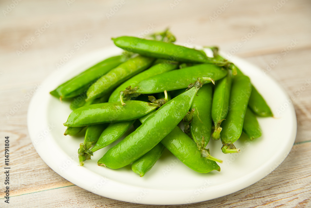 Green pea pods on the big white plate. Green pea pods on the big white plate.
