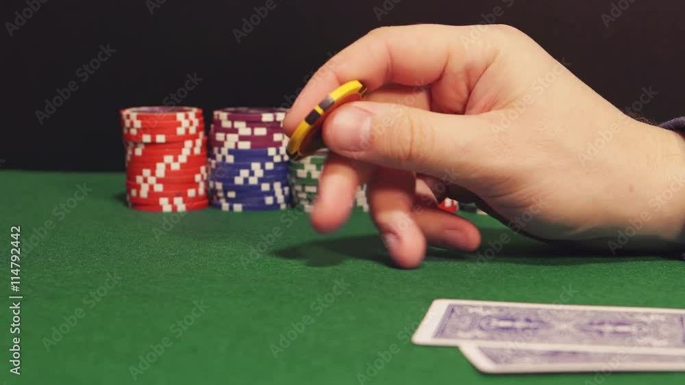 POKER: Player twirls a playing chip in the hand and thinks (side view) POKER: Player twirls a playing chip in the hand and thinks (side view)