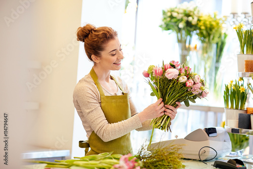 smiling florist woman making bunch at flower shop photo