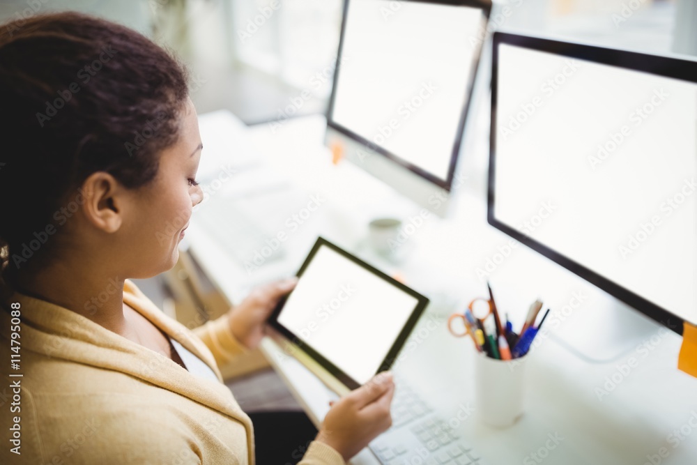 Businesswoman using digital tablet at desk in creative office Businesswoman using digital tablet at desk in creative office