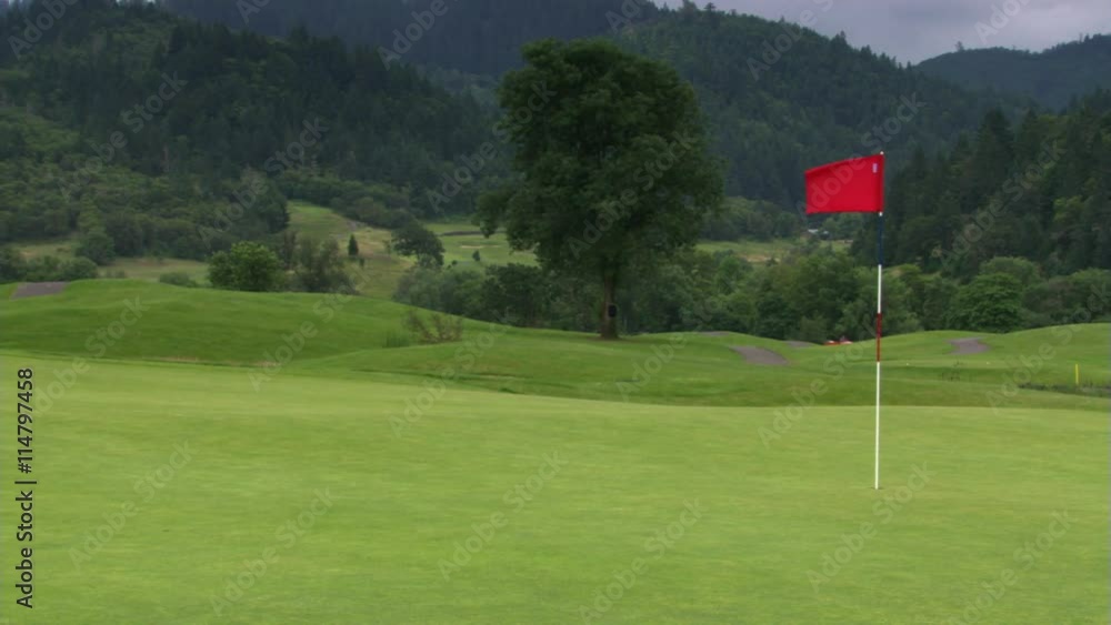 Red flag waving above hole on hilly golf course Red flag waving above hole on hilly golf course