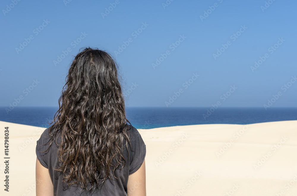 brunette woman looking at sea from a white dune in Fuerteventur brunette woman looking at sea from a white dune in Fuerteventur