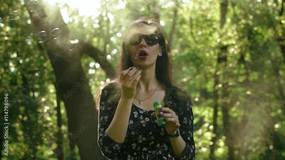 Cute girl with sunglasses blowing bubbles in the park with smoke slow-motion Cute girl with sunglasses blowing bubbles in the park with smoke slow-motion