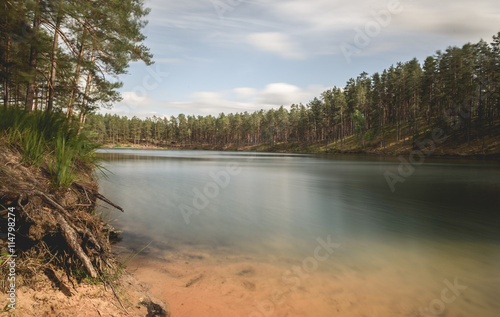 sky and clouds reflecting in forest lake