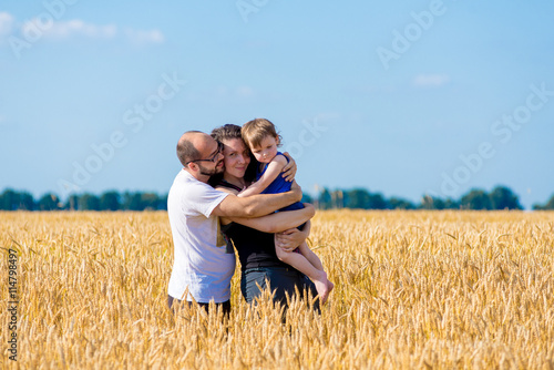 Happy smiling family standing on wheat field