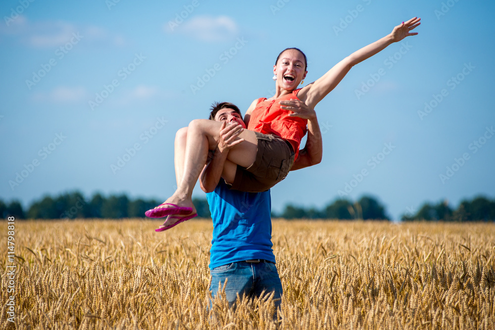 The guy carries the girl on sunset wheat field The guy carries the girl on sunset wheat field