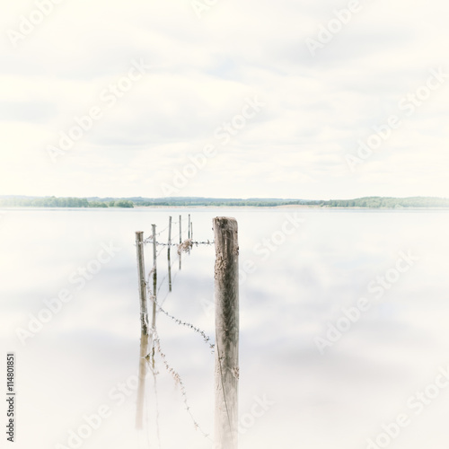 Lake with a barbed wire fence and wooden posts photo