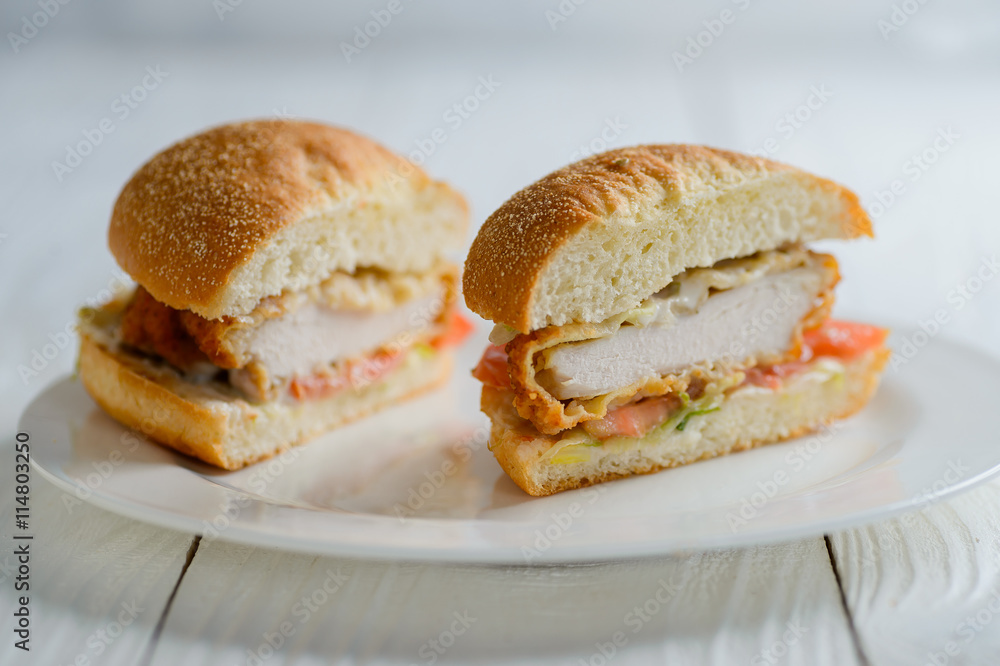 Fresh tasty chicken burger sectional view on wooden table Fresh tasty chicken burger sectional view on wooden table