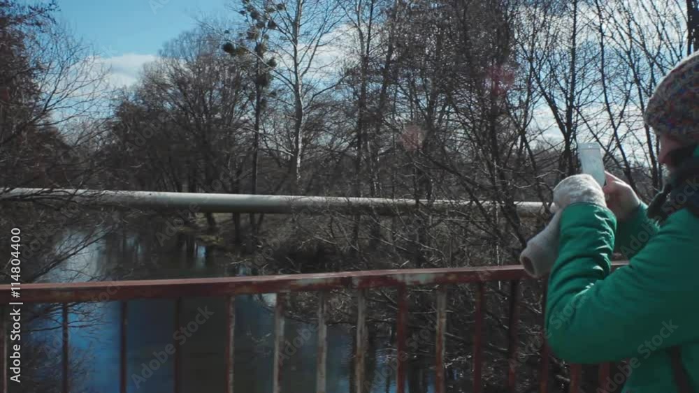 Girl takes photo of the river from the bridge Girl takes photo of the river from the bridge