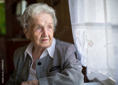 An elderly woman, sitting at the table, a portrait.