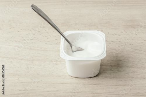 White milk Yogurt with silver spoon on a wooden background