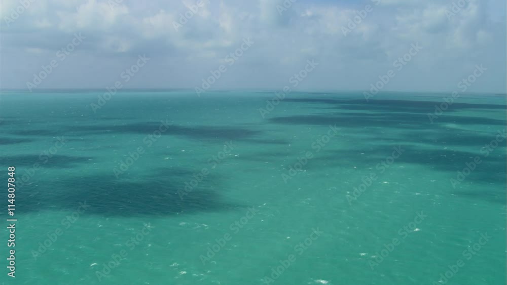 Flight over green ocean water dappled by cloud shadow Flight over green ocean water dappled by cloud shadow