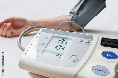 Patient suffers from hypertension. Woman is measuring blood pressure with digital monitor. photo