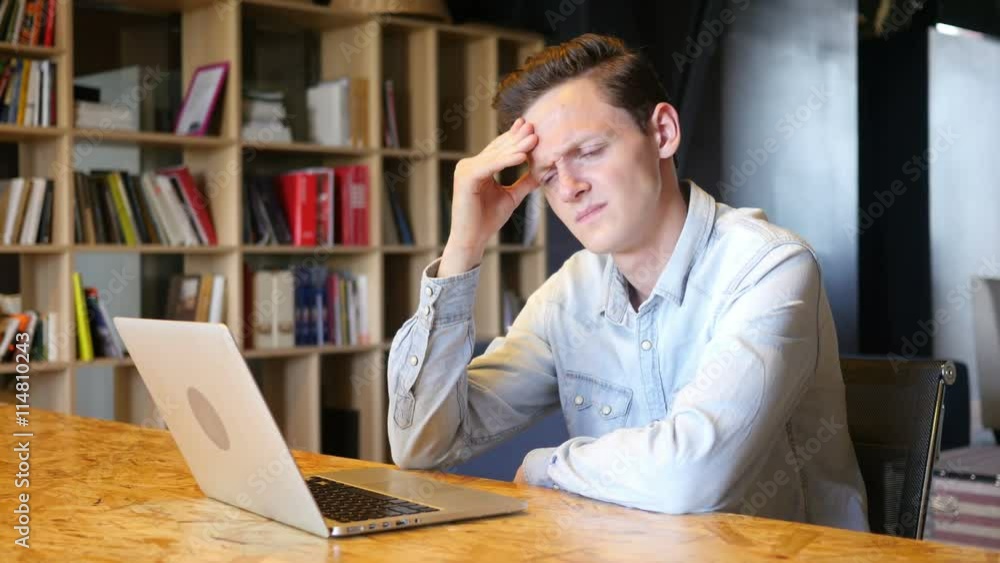 Handsome young stressed businessman sitting in his office using laptop Handsome young stressed businessman sitting in his office using laptop