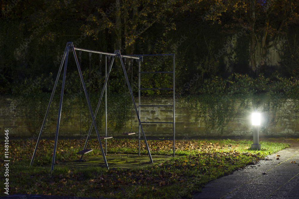 Ein leerer Spielplatz mit Kinderschaukeln nachts mit Nebel und gruseliger Atmosphäre Ein leerer Spielplatz mit Kinderschaukeln nachts mit Nebel und gruseliger Atmosphäre