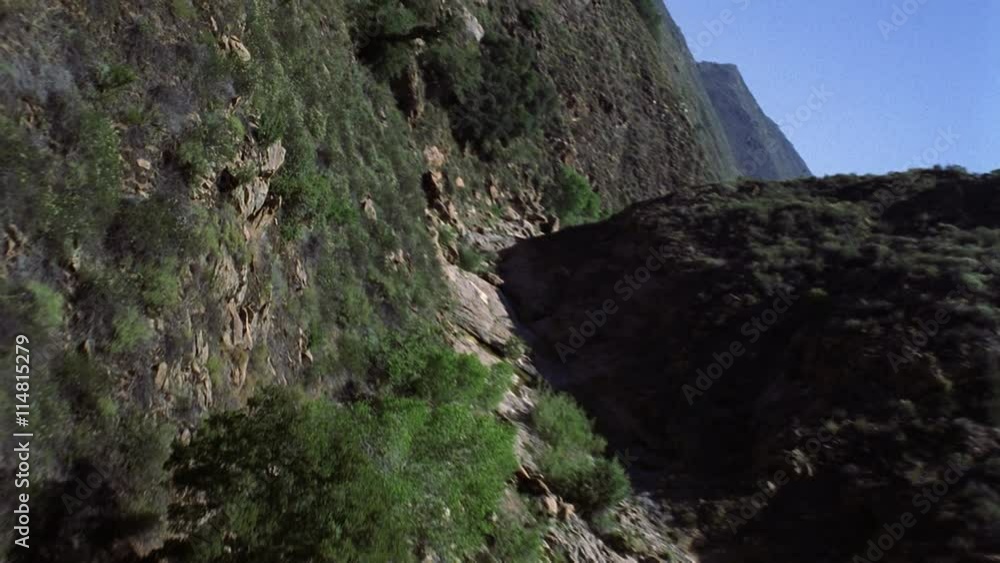 Tilting flight through brushy canyon. Shot in 202.