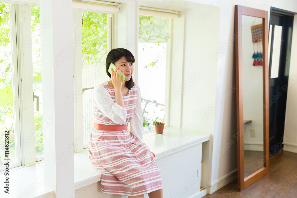 部屋で電話をする女性 部屋で電話をする女性