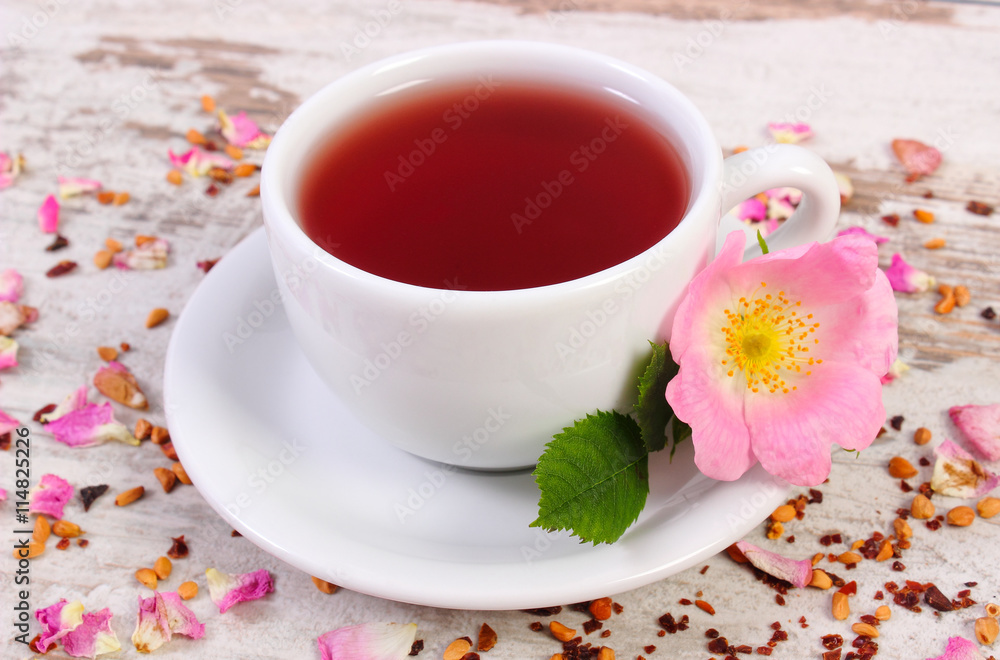 Cup of tea with wild rose flower on old rustic wooden background Cup of tea with wild rose flower on old rustic wooden background