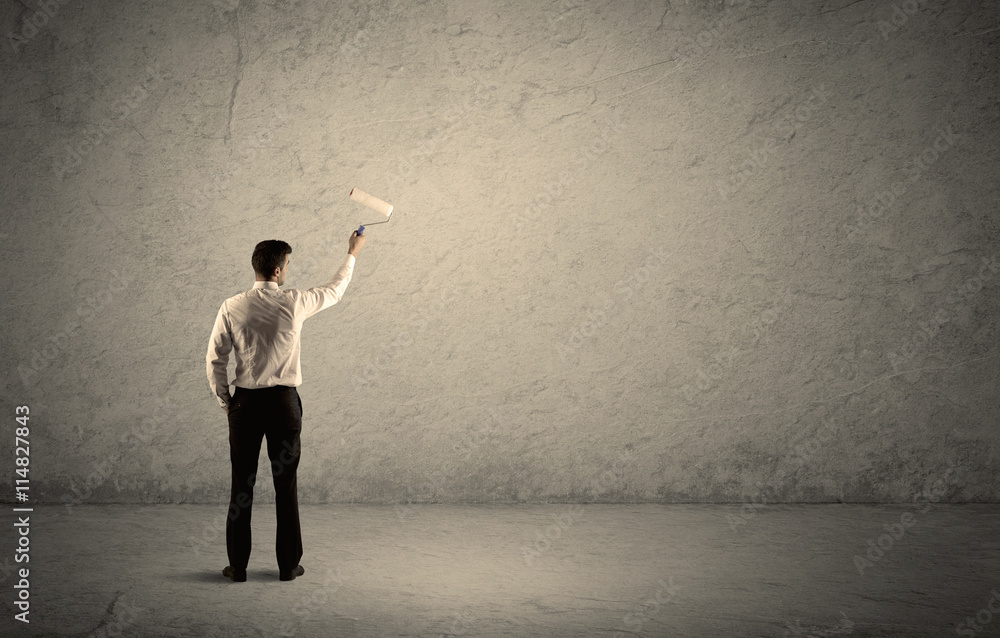 Salesman with roller standing at empty wall Salesman with roller standing at empty wall