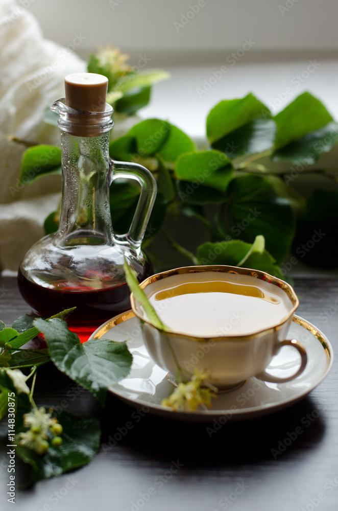 porcelain Cup of Linden tea and Maple syrup on a background of dark wood porcelain Cup of Linden tea and Maple syrup on a background of dark wood
