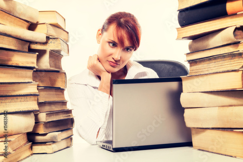 Education concept. Beautiful young woman with stack of books with her laptop on white background photo