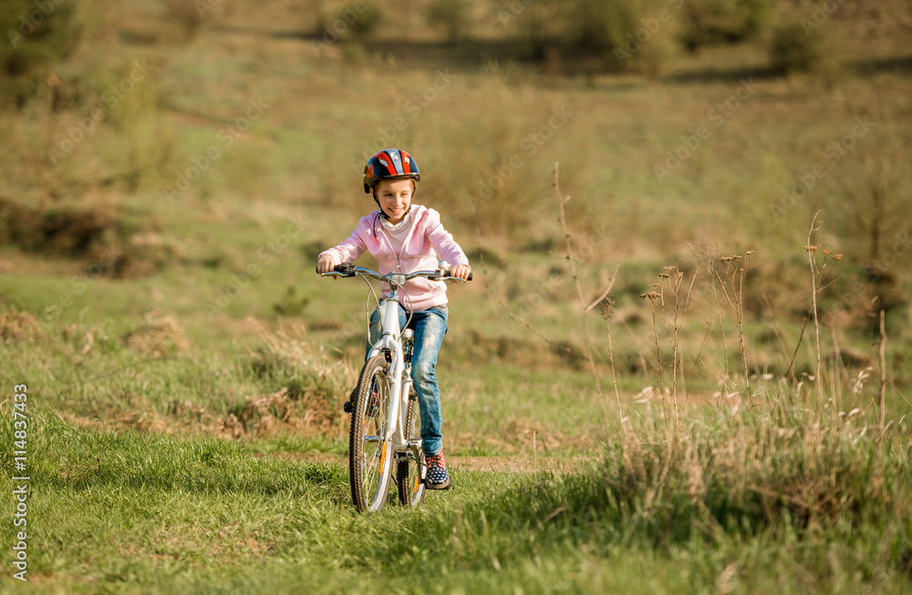 smiling little girl riding a bike in helmet 
