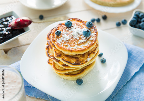 pancakes with blueberry and jam on white wooden table