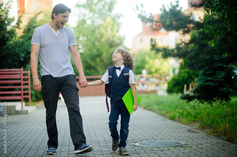 Cute little first grader is going with his father to school. Cute little first grader is going with his father to school.