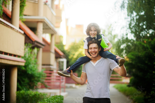The father carries the son to school on shoulders