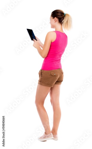 back view of standing young beautiful girl with tablet computer