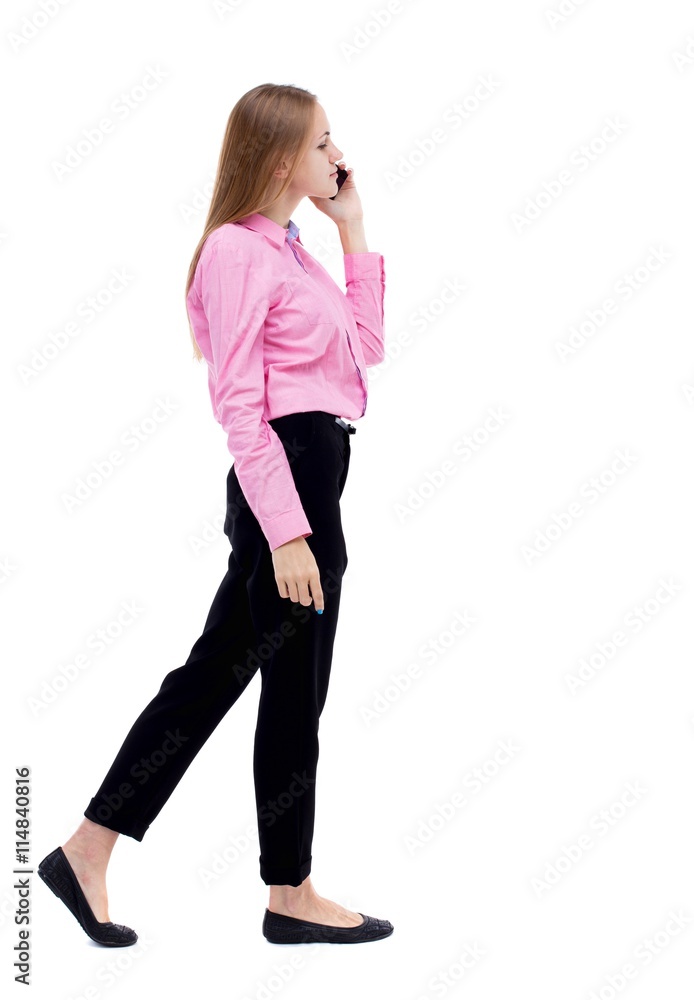 side view of a woman walking with a mobile phone. back view ofgi side view of a woman walking with a mobile phone. back view ofgi
