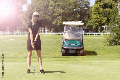 hübsche Golferin im Kleid mit Golfcar