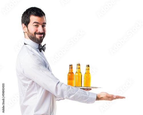 Waiter with beer bottles on the tray presenting something