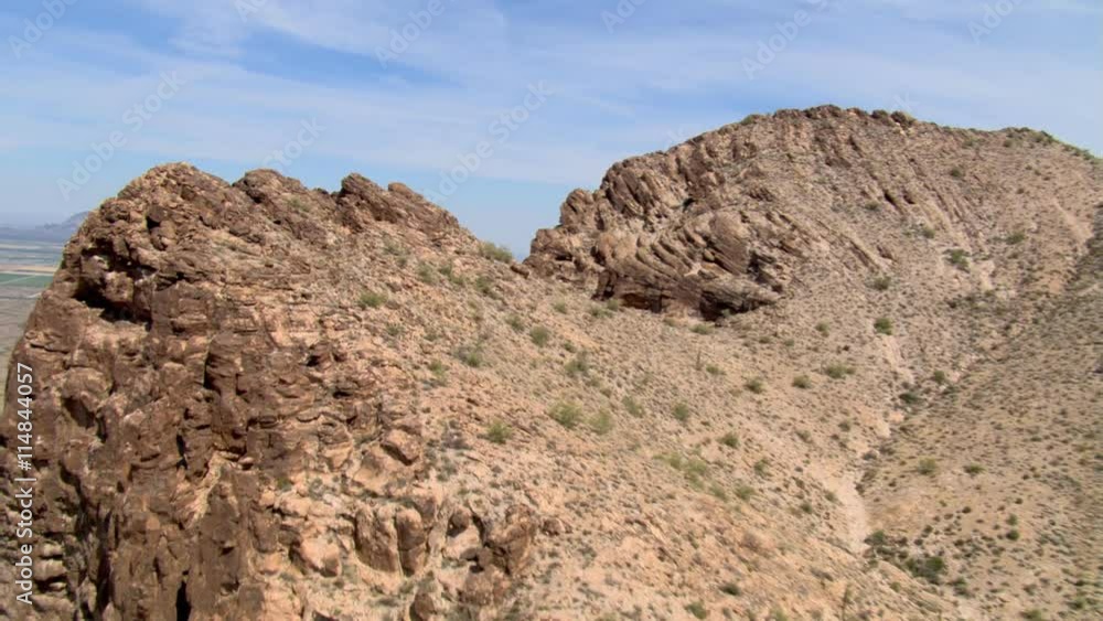 Flight over a rugged cliff top with desert and agricultural land spread below Flight over a rugged cliff top with desert and agricultural land spread below