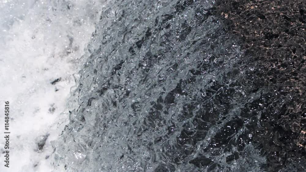 Silvery ultra-slow motion water gliding over a rock ledge into a foaming pool Silvery ultra-slow motion water gliding over a rock ledge into a foaming pool