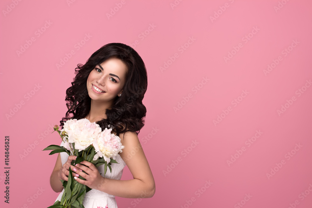 Beautiful smiling girl with flowers on pink background